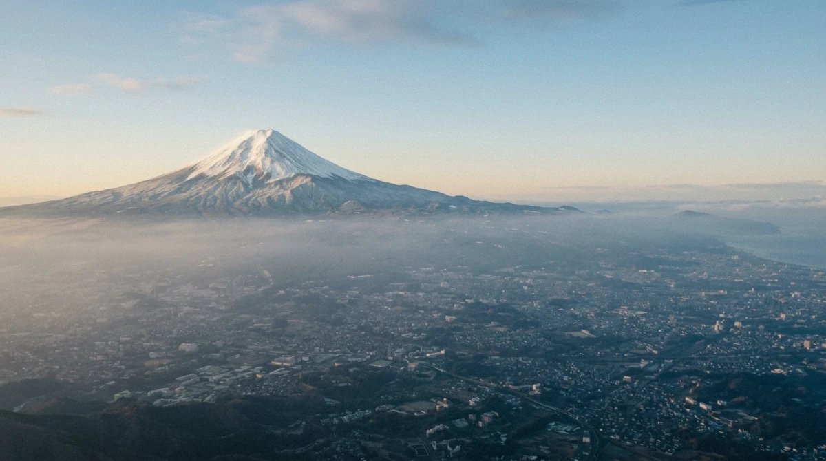 Snow-capped Mount Fuji rising above a low haze layer seen from the air, the clear-winter payoff of a Tokyo helicopter tour